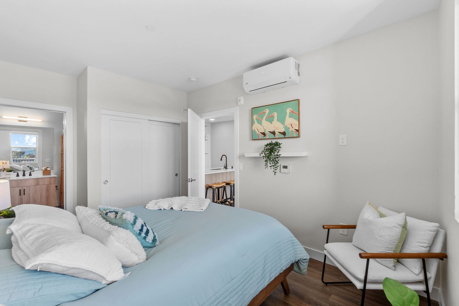 Bedroom with blue bedding, white walls, and a small sitting area.