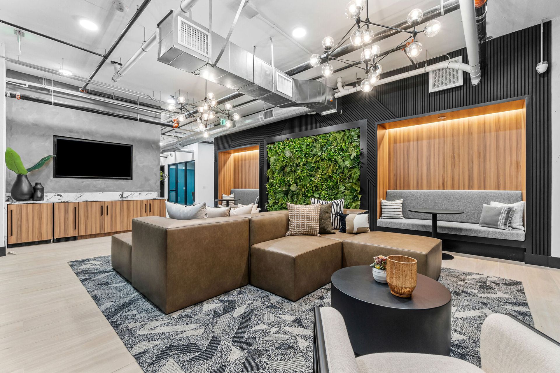 Modern lounge area with sectional sofa, green wall, and decorative lighting.