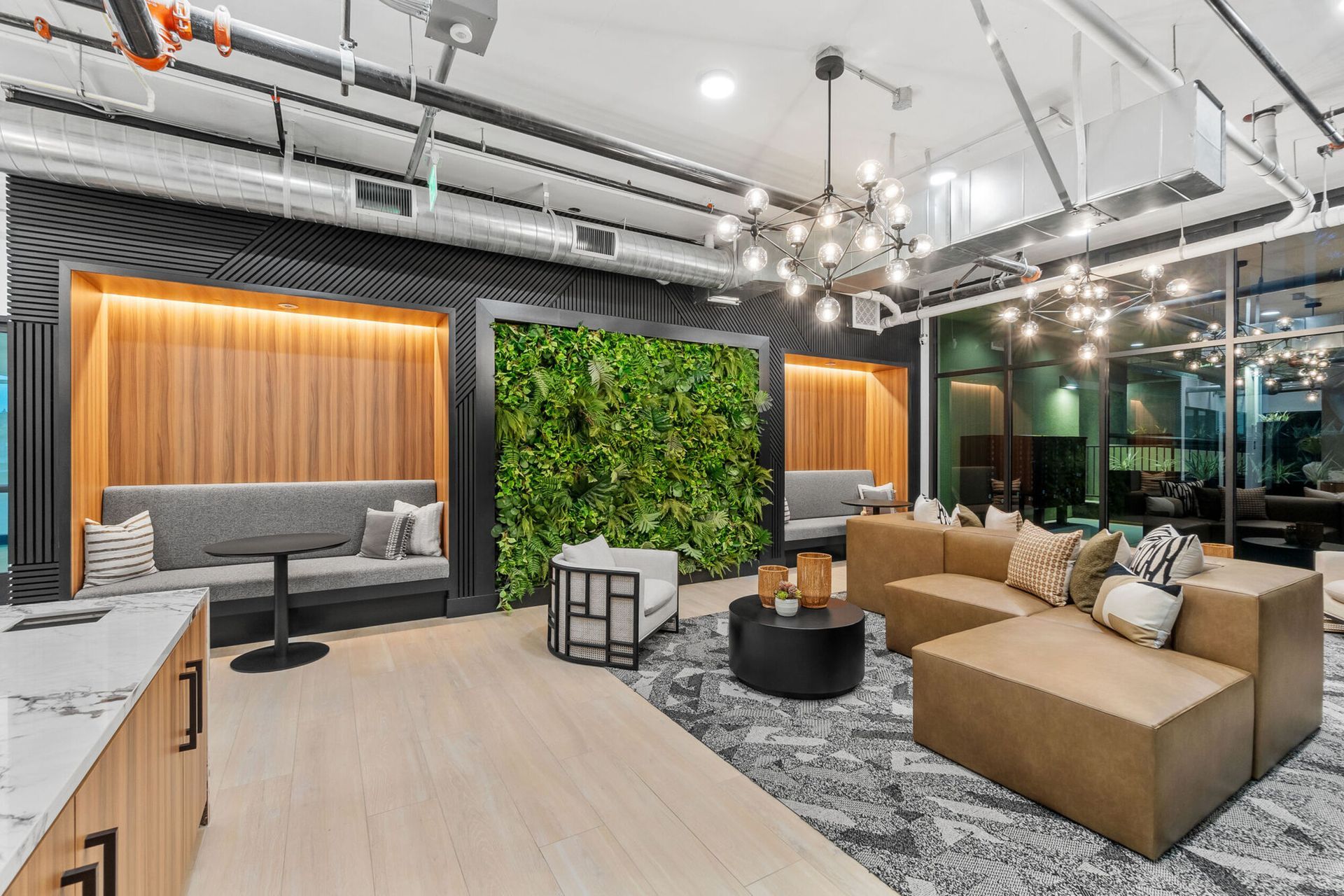 Modern lounge area with a sofa, seating alcoves with plants, and a black coffee table.