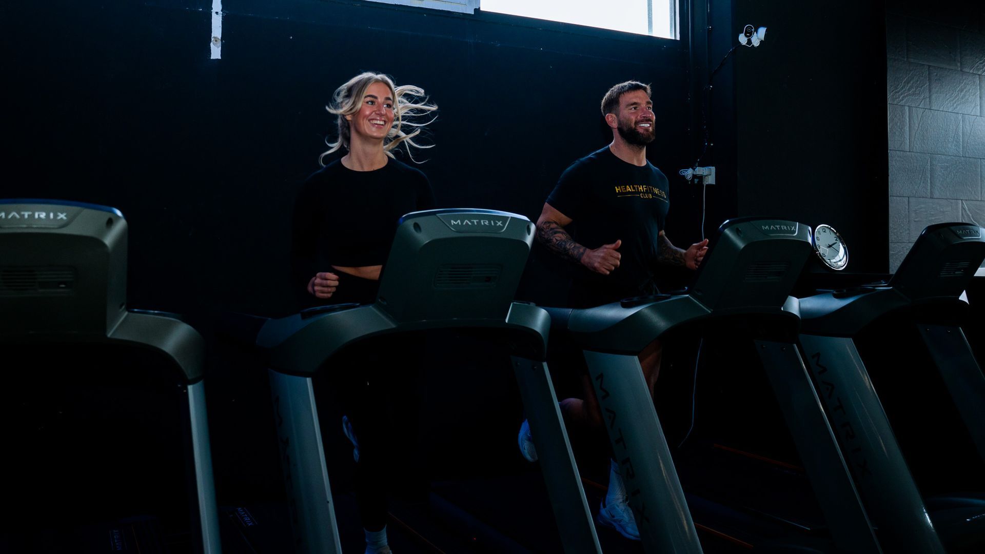Een man en een vrouw rennen op een loopband in een sportschool.