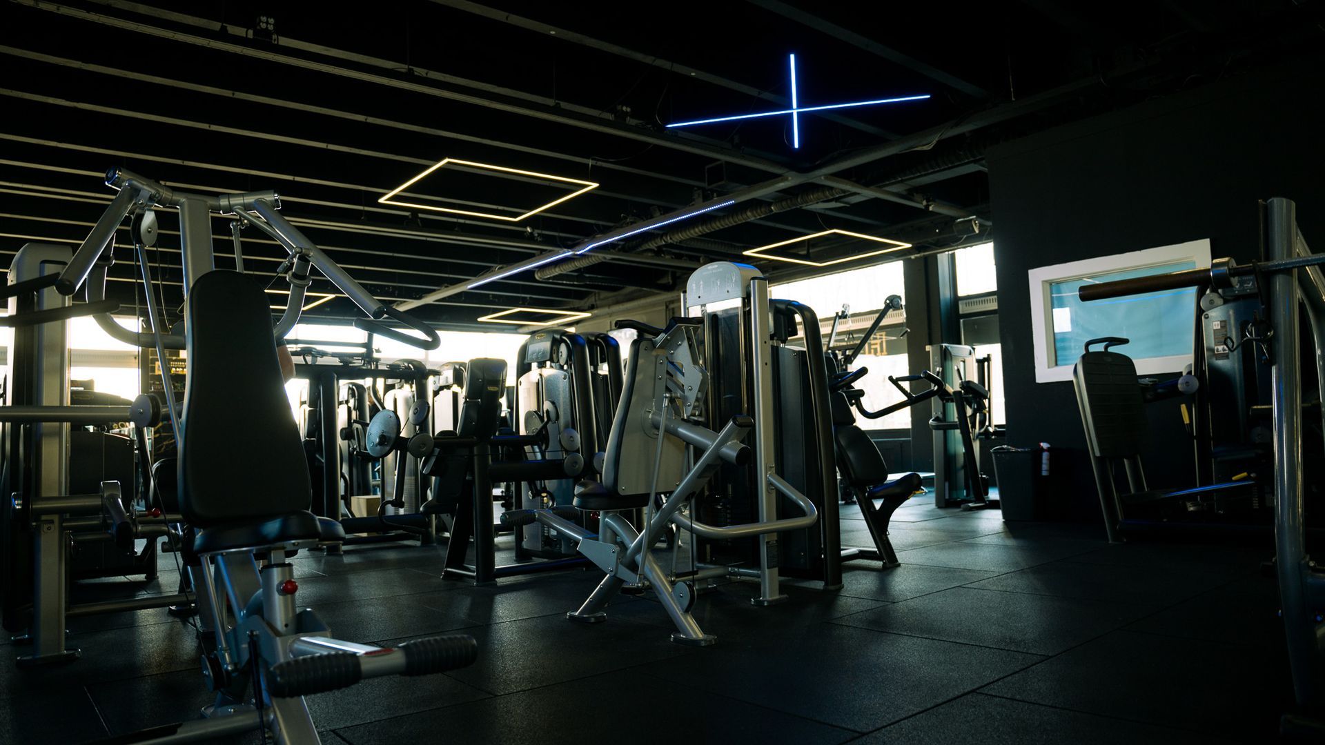 Een sportschool vol met fitnessapparatuur en een blauw licht op het plafond.
