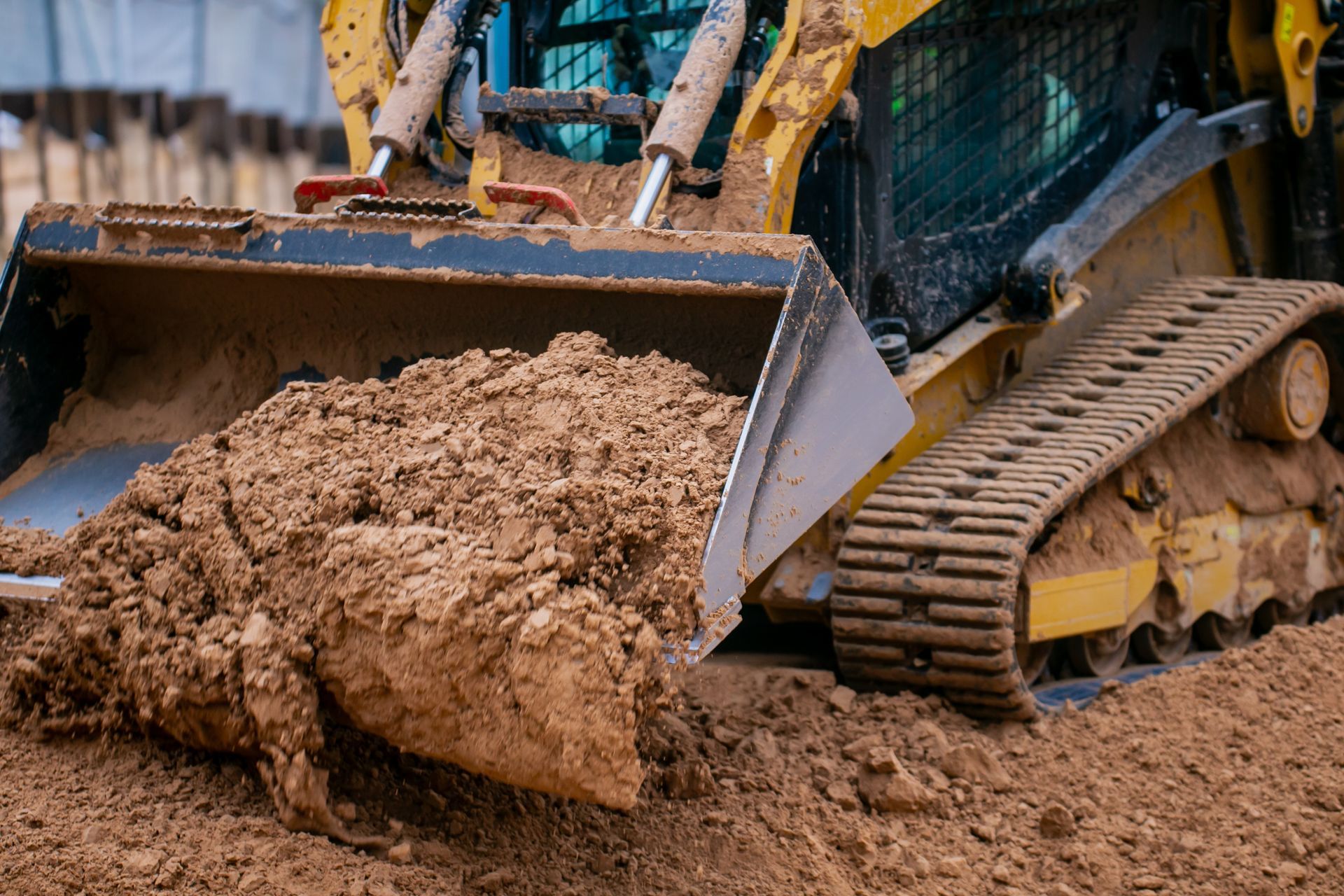 Orange excavator digging beside a road under a blue sky, dirt mound in foreground, trees in background. Orange excavator digging beside a road under a blue sky, dirt mound in foreground, trees in background.