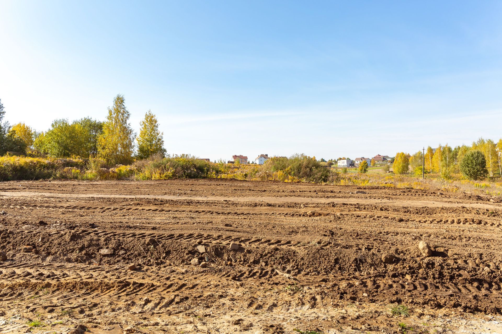 Plowed field, earth-toned, under a clear blue sky, with trees in the background. Plowed field, earth-toned, under a clear blue sky, with trees in the background.