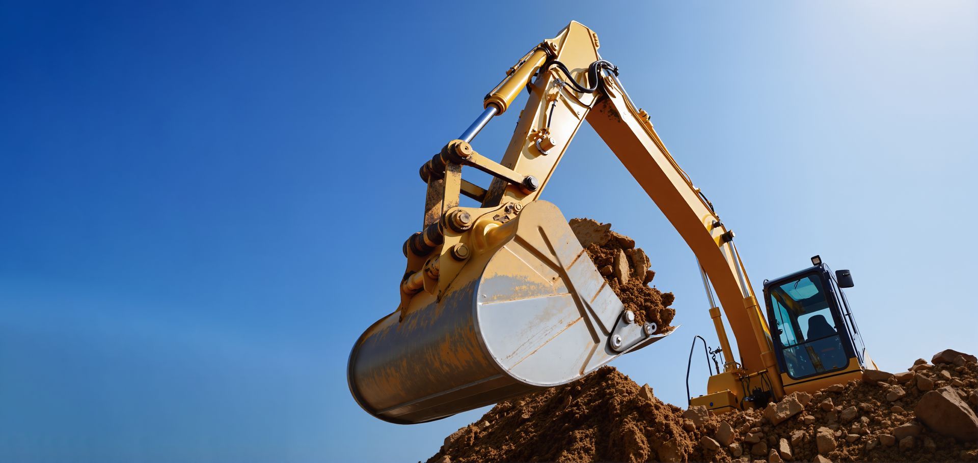 Yellow excavator digging dirt under a bright blue sky. Yellow excavator digging dirt under a bright blue sky.