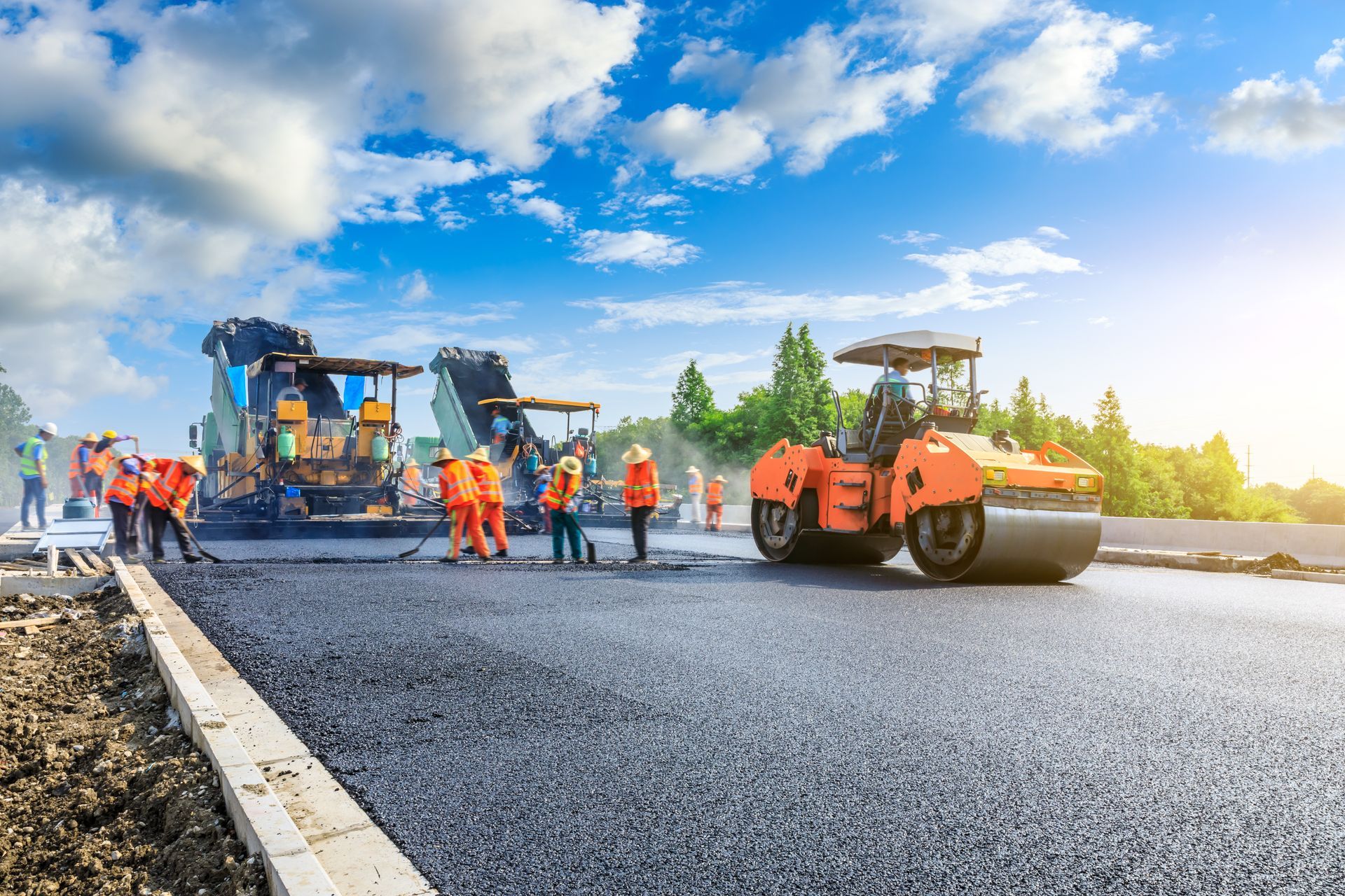 Road construction: Asphalt being laid by machinery, workers in orange vests. Sunny day, blue sky. Road construction: Asphalt being laid by machinery, workers in orange vests. Sunny day, blue sky.