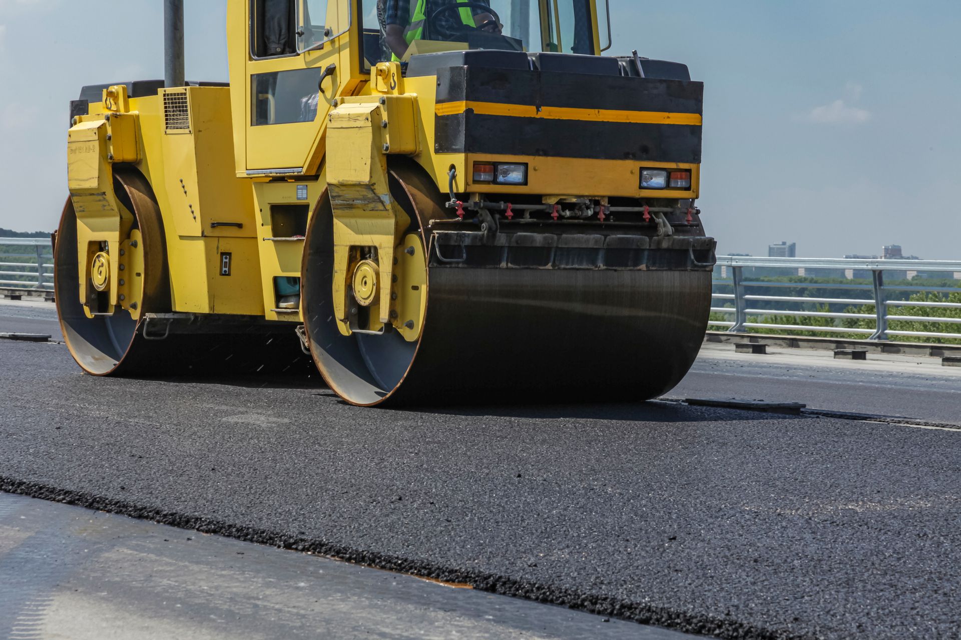 Road worker compacts asphalt on a pothole.