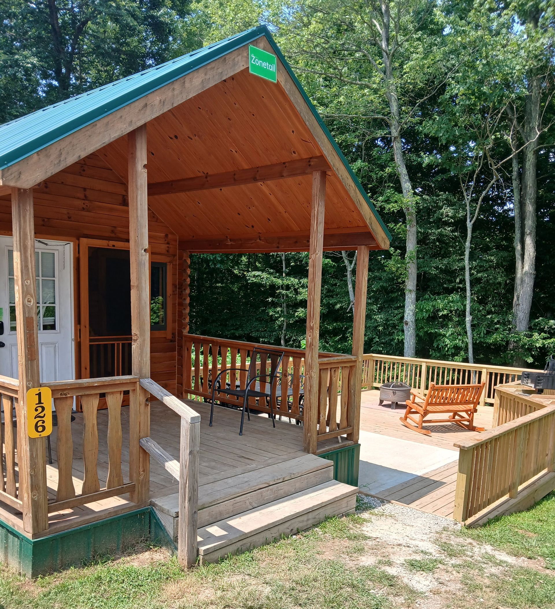 a small wooden cabin with a porch in the middle of a forest .