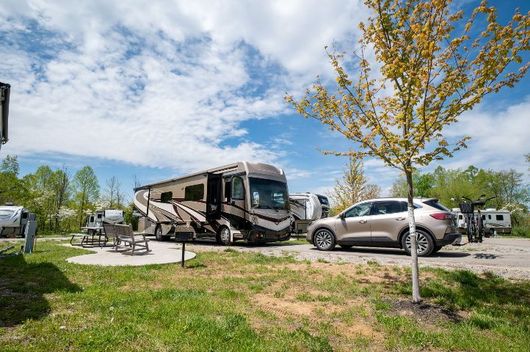 a rv and a car are parked in a campground .