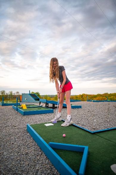 a young woman is playing mini golf on a rooftop .