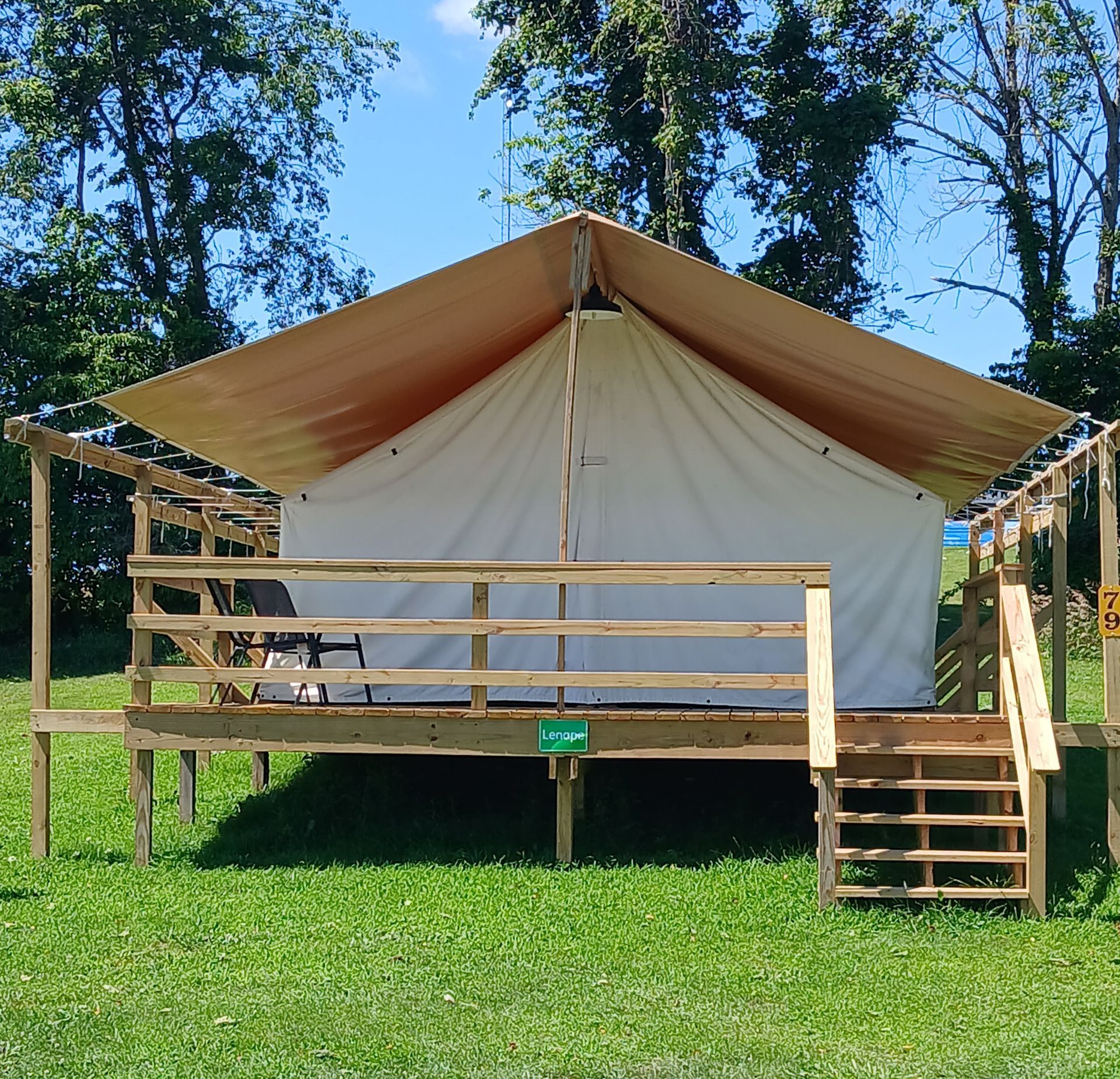 a tent is sitting in the middle of a grassy field .