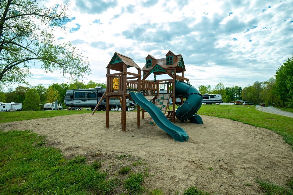 a playground with a slide and swings in the middle of a field .