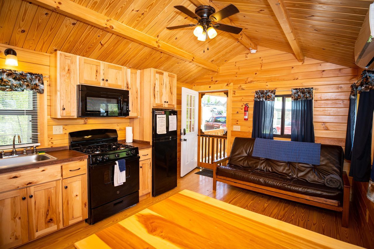 a small log cabin with a porch in the middle of a forest .