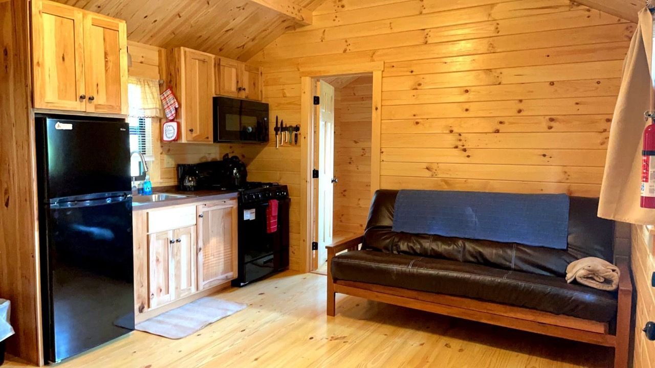 a small log cabin with a deck and stairs in the woods .