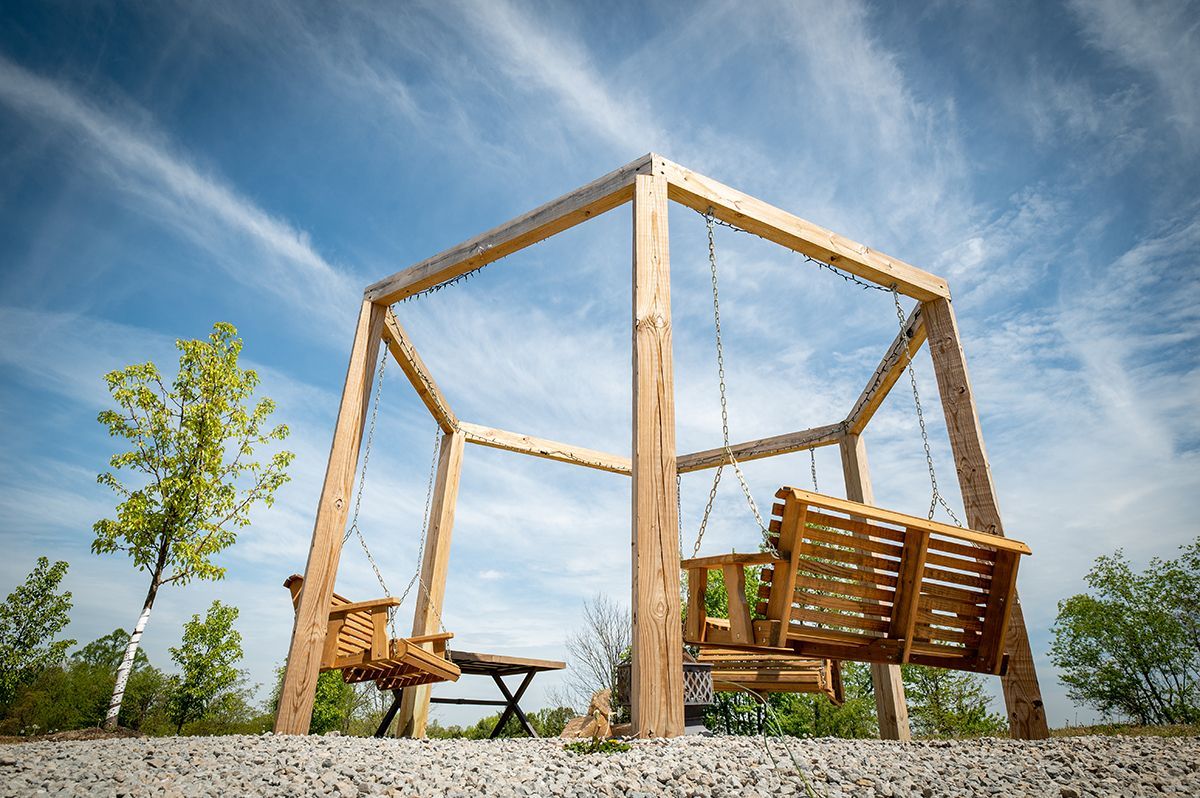 a wooden swing is sitting under a wooden structure .