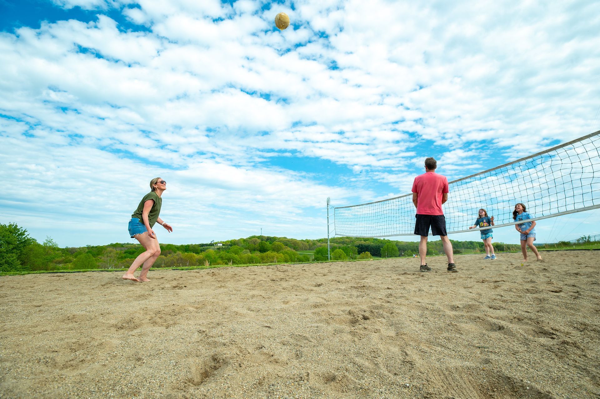 a group of people are playing volleyball on a sandy beach .
