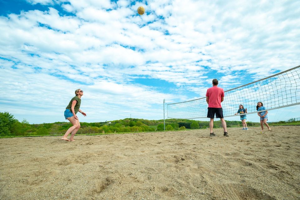 a group of people are playing volleyball on a sandy court.
