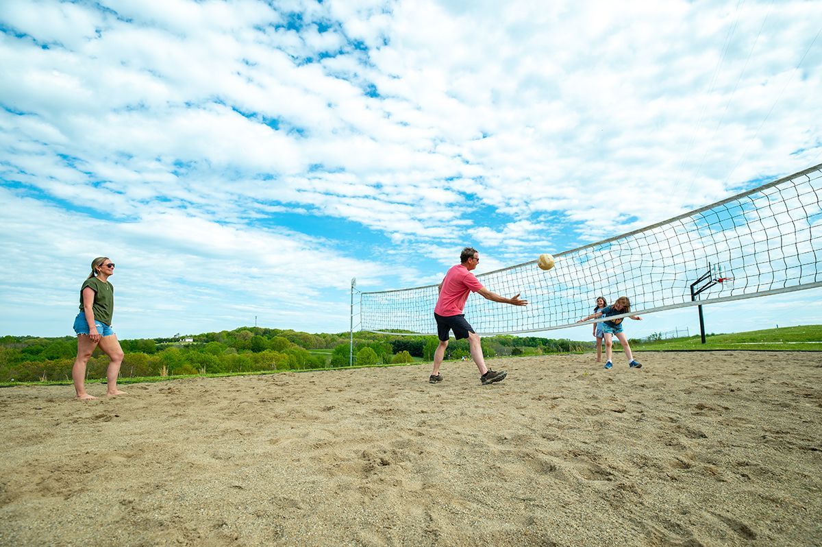 a group of people are playing volleyball on a sandy beach .