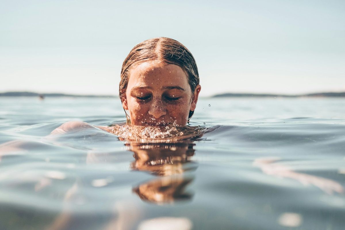 a woman is swimming in the ocean with her eyes closed .