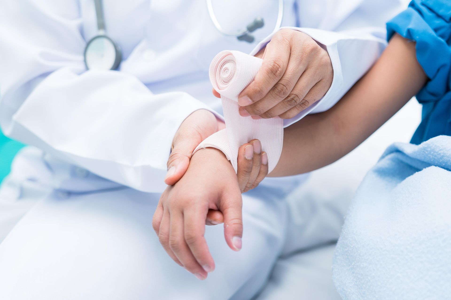 A doctor is wrapping a child 's wrist in a bandage.