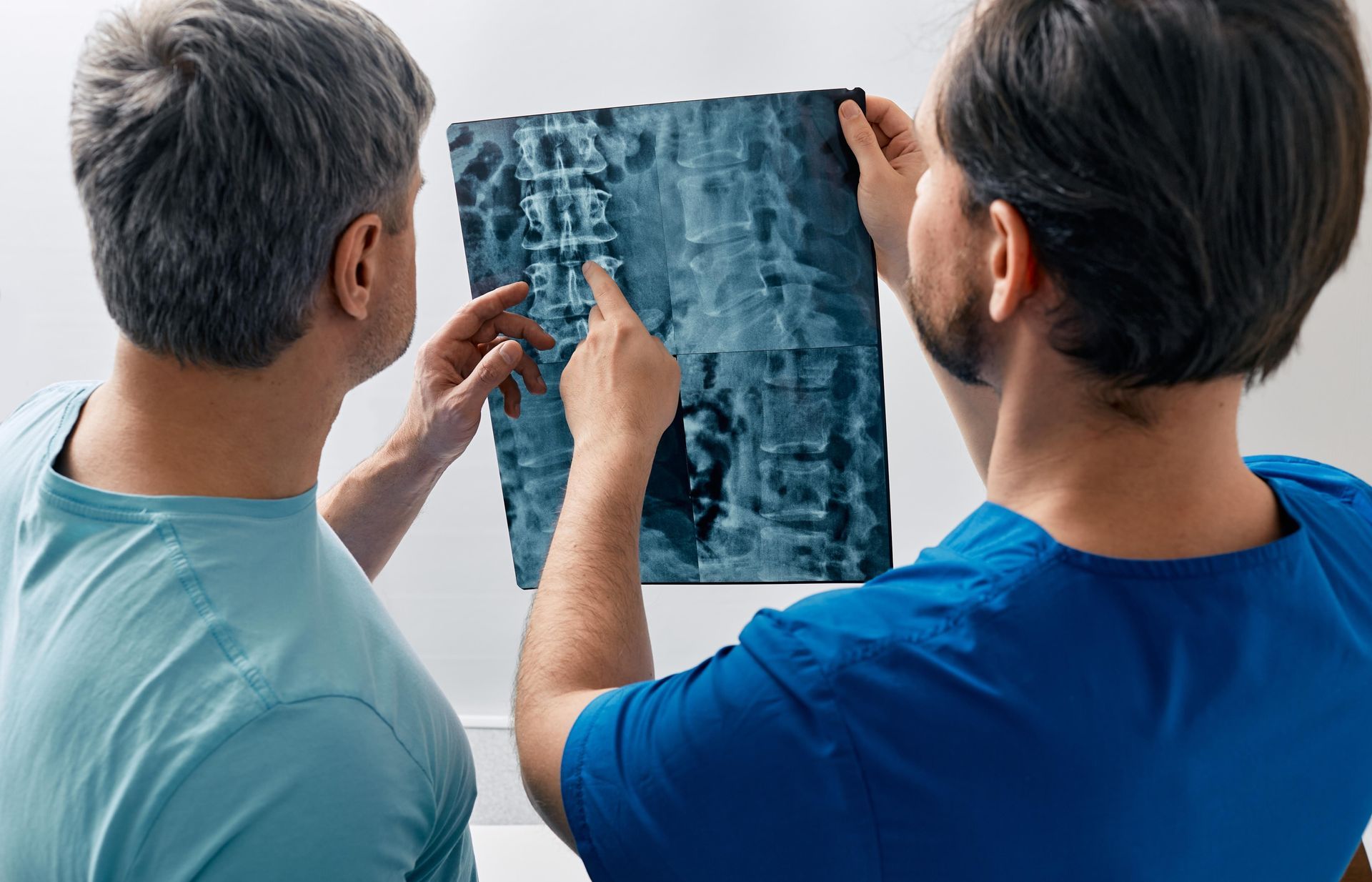 Two men are looking at an x-ray of a person 's back.