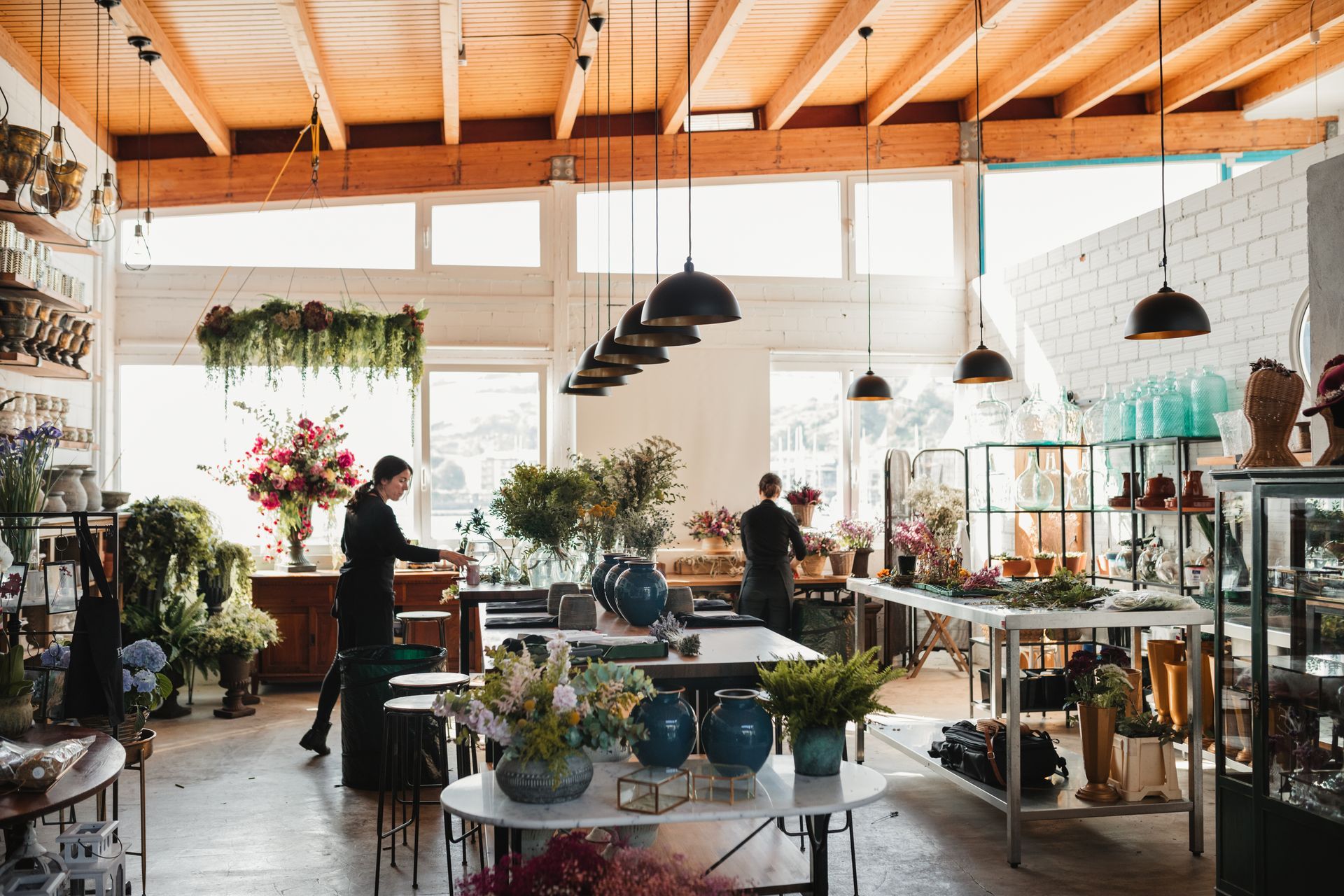 Interior plant design services showroom with staff arranging flowers and plants in modern space.
