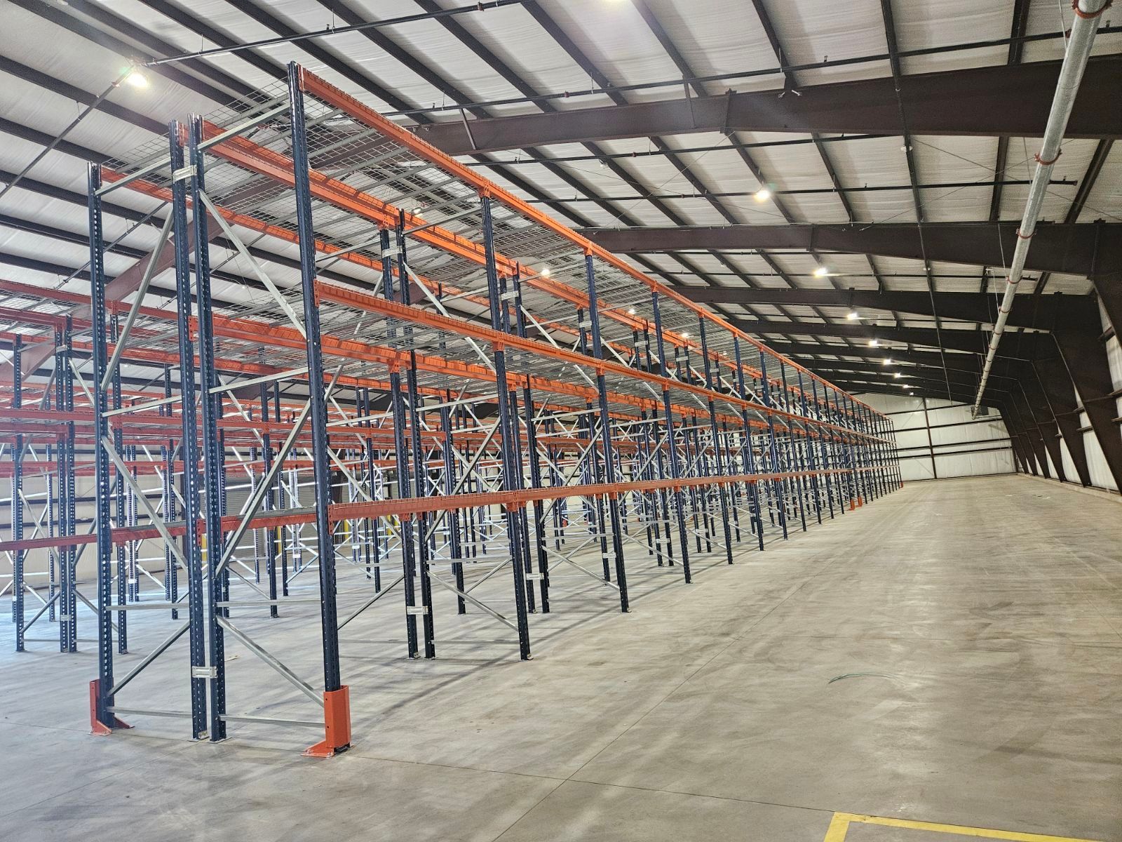 A large warehouse filled with pallet racks and a concrete floor.