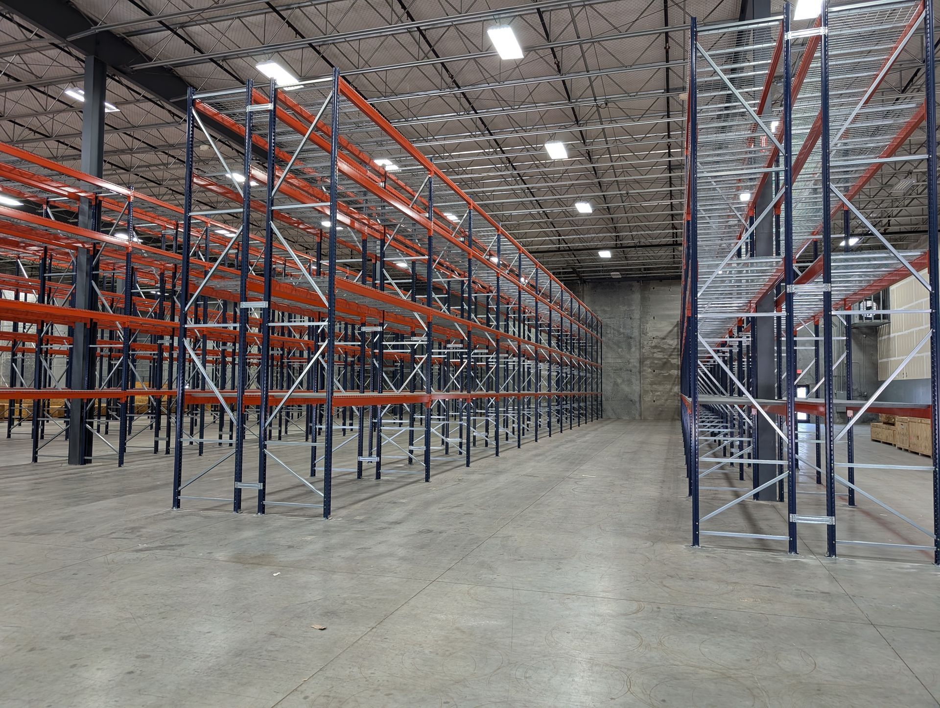 An empty warehouse with red shelves and a concrete floor.