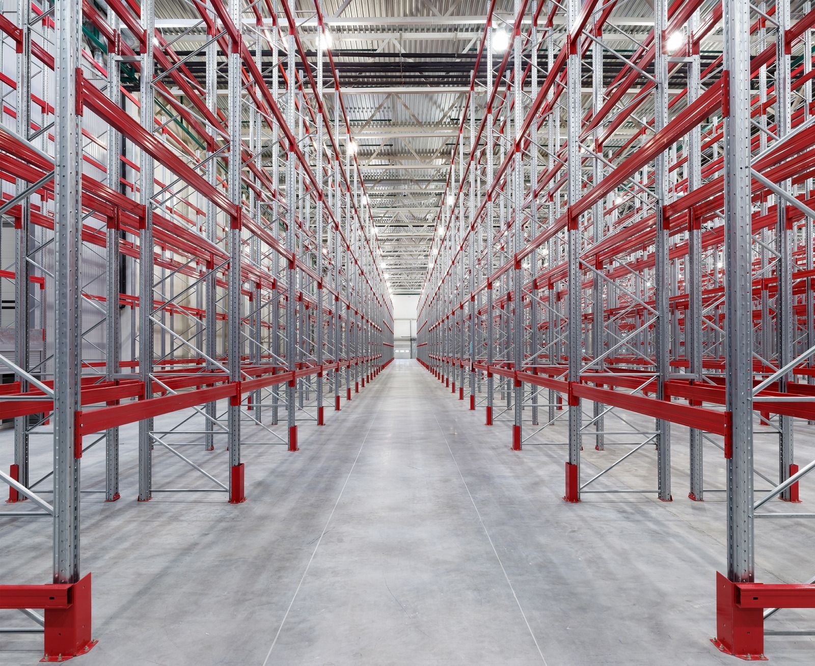 An empty warehouse with red shelves and a concrete floor.