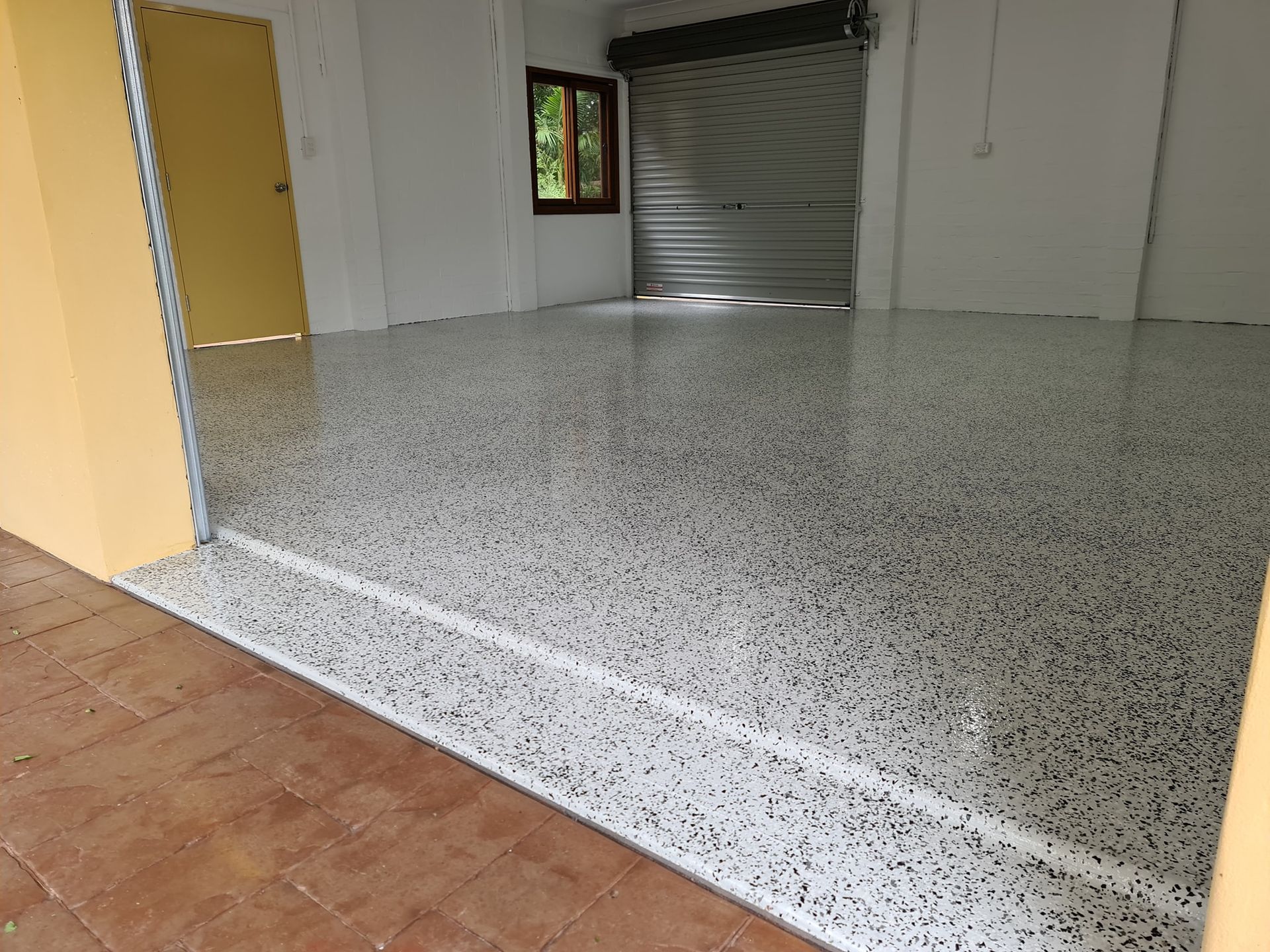 A garage with a tiled floor and a garage door.— That Painter Guy In South Nowra, NSW