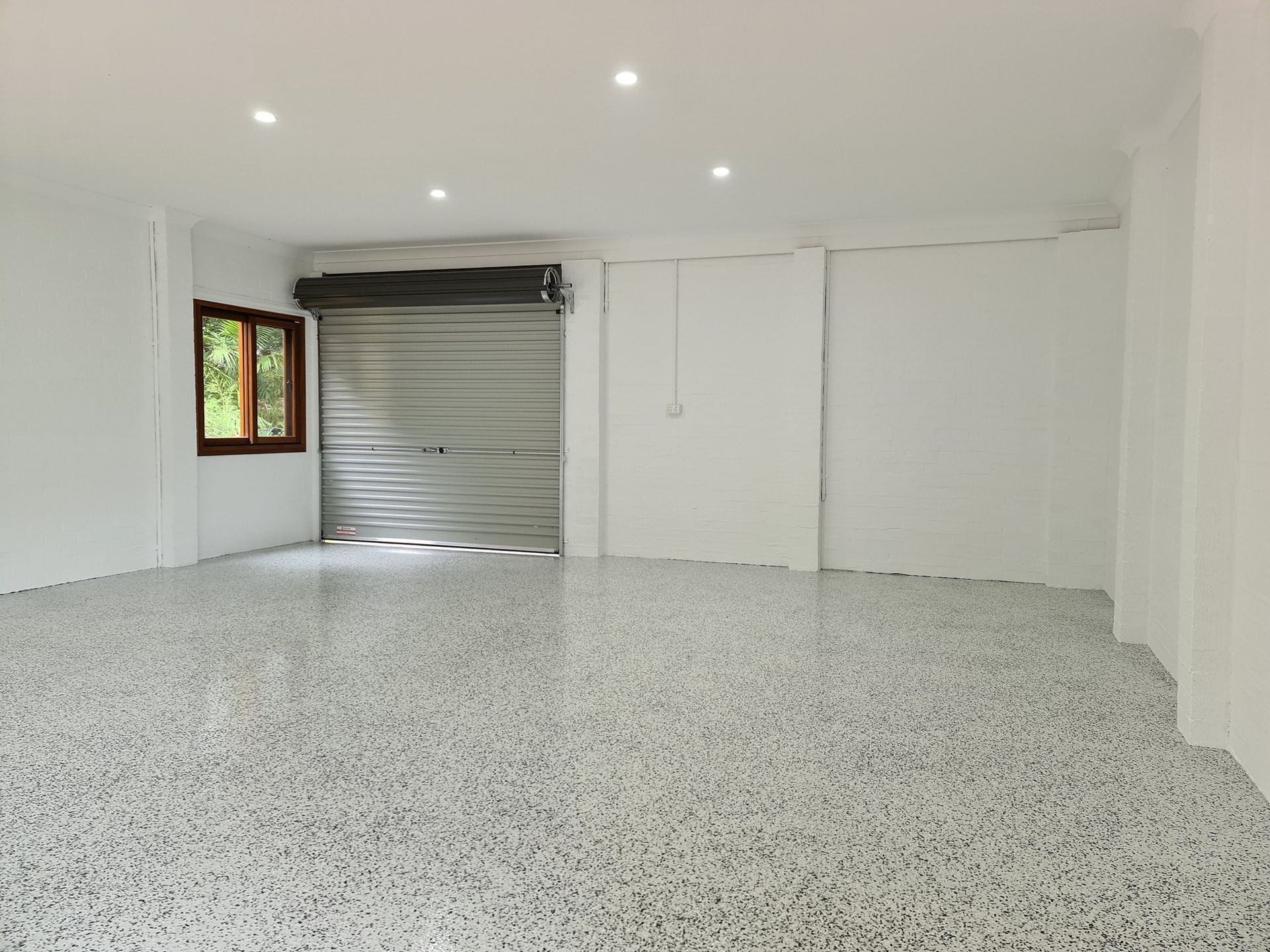 An empty garage with a garage door and a window.— That Painter Guy In South Nowra, NSW