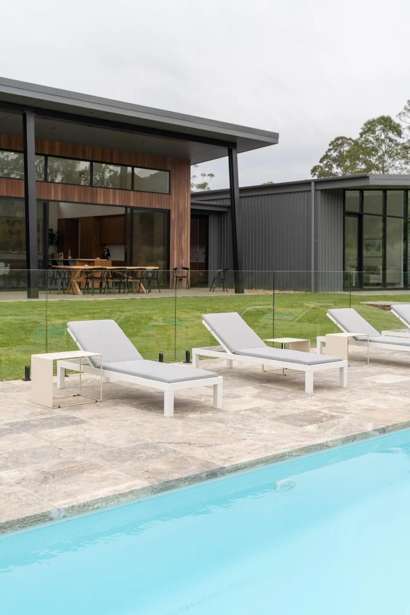A Row Of Lounge Chairs Are Sitting Next To A Swimming Pool In Front Of A House  — That Painter Guy In South Nowra, NSW