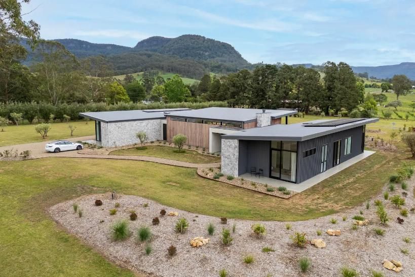 An Aerial View Of A Modern House In The Middle Of A Grassy Field With Mountains In The Background  — That Painter Guy In South Nowra, NSW