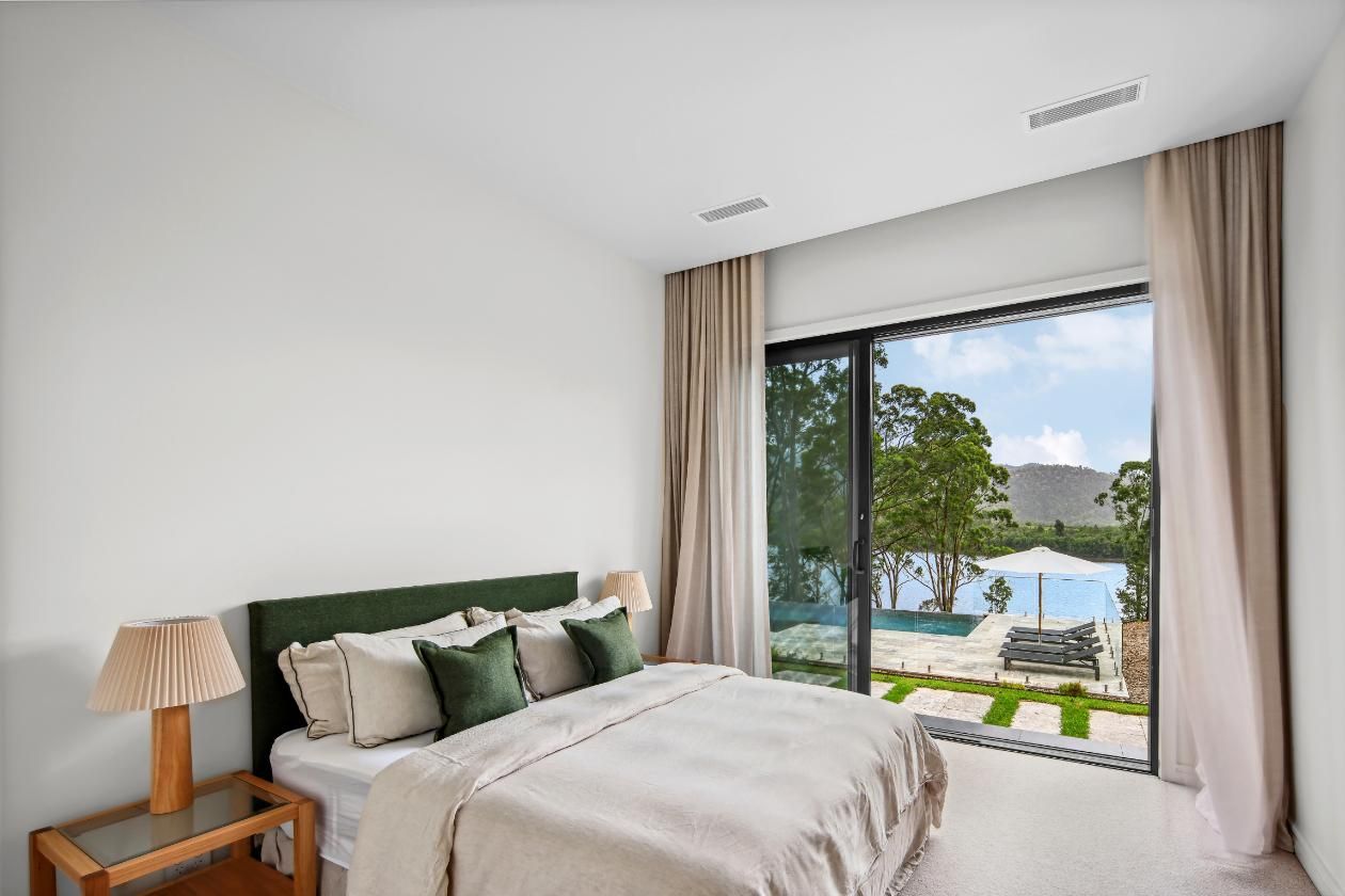 A Bedroom With A Large Bed and A Sliding Glass Door Leading To A Pool  — That Painter Guy In South Nowra, NSW