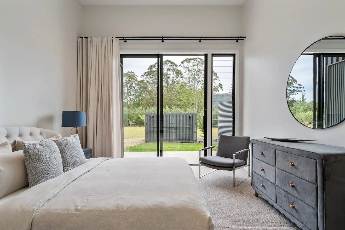 A bedroom with a bed , chair , dresser , mirror and sliding glass doors.— That Painter Guy In South Nowra, NSW