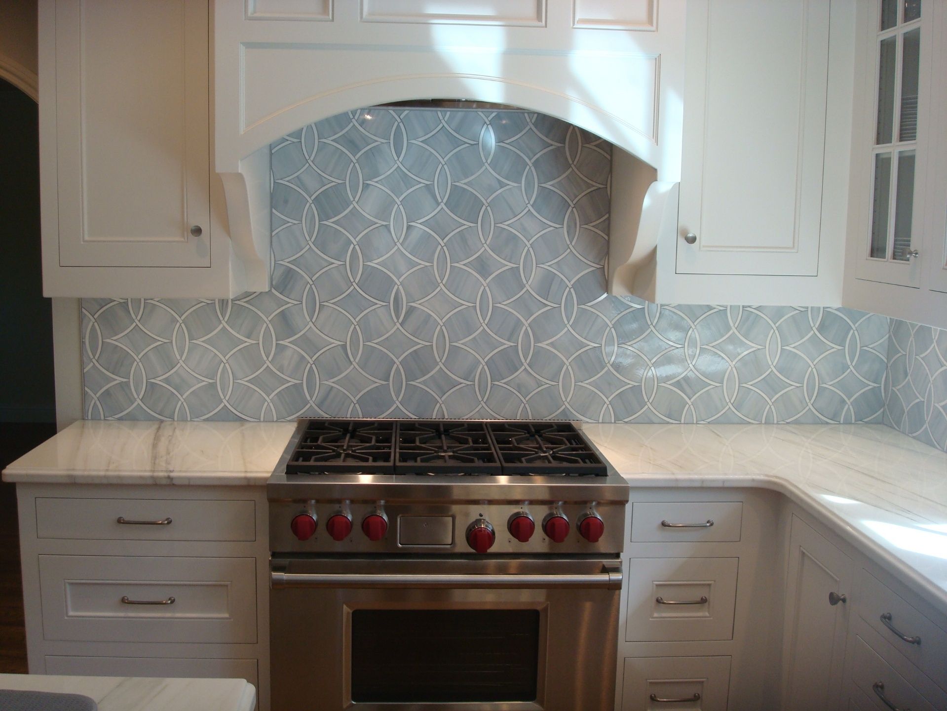 A kitchen with a stove top oven and white cabinets