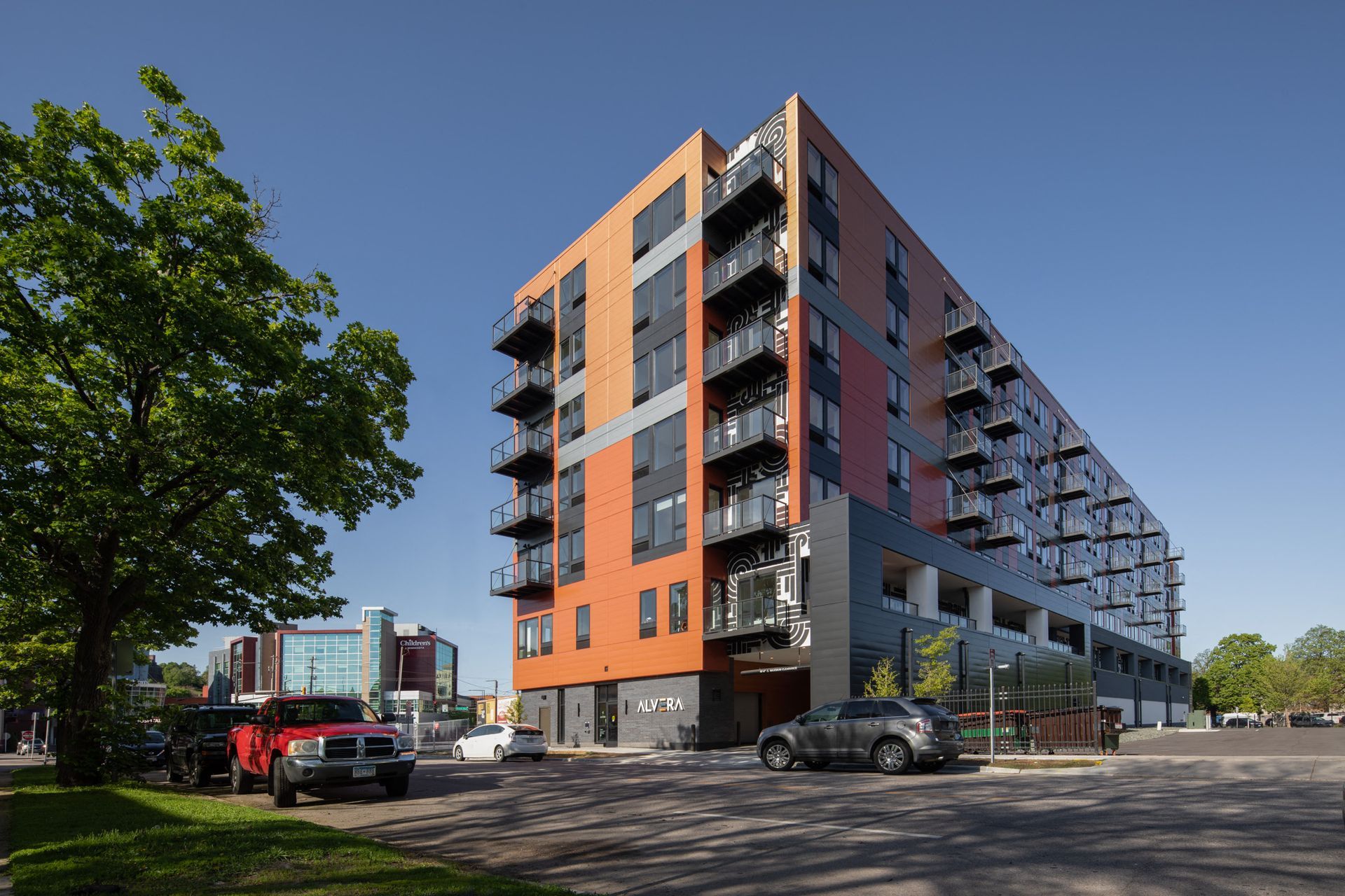 Exterior view of a modern apartment building with balconies and a tree in the foreground