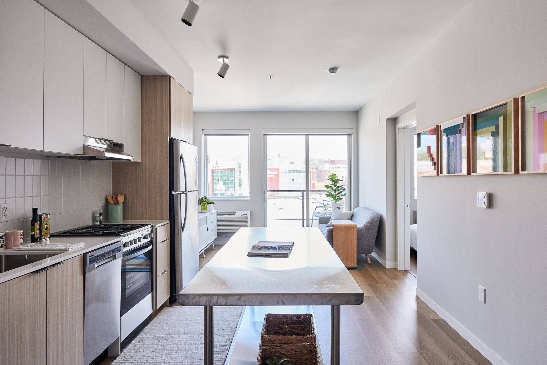 Modern apartment kitchen with an island and stainless appliances overlooking the living area.