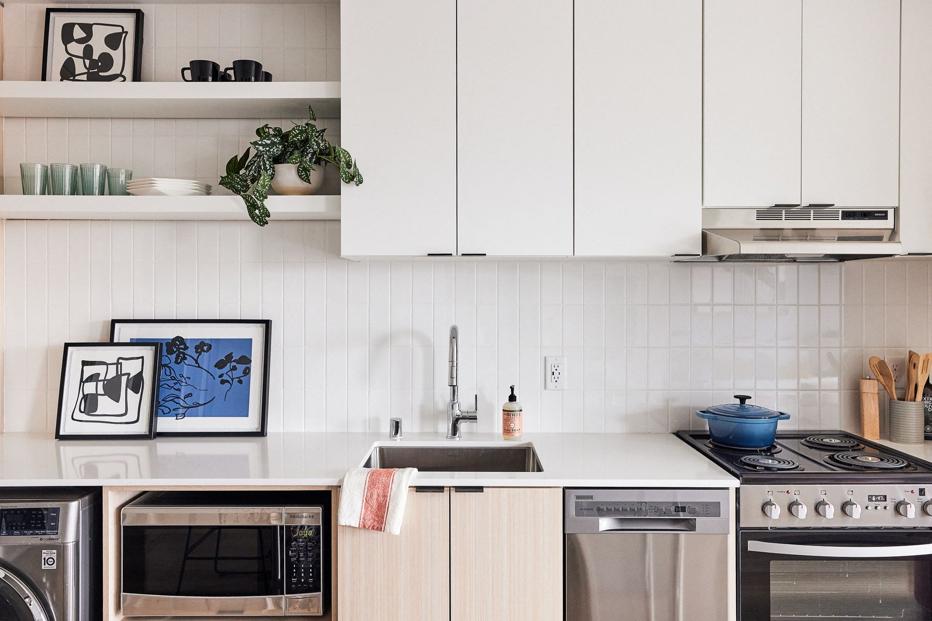 Modern kitchen with white cabinets, sink, and stainless-steel appliances.