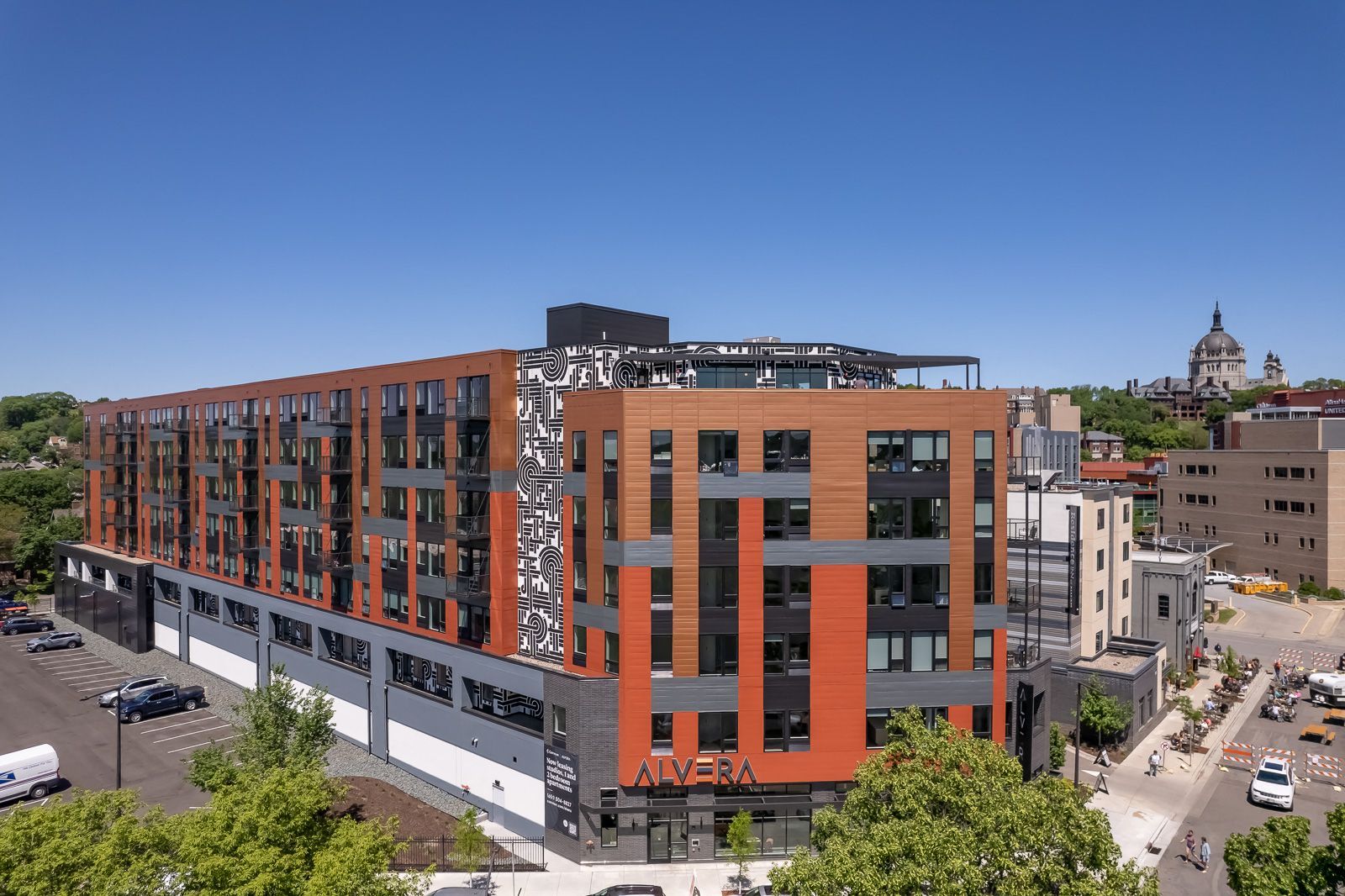 Modern multi-story apartment building with orange and gray panels and a bold black-and-white mural.