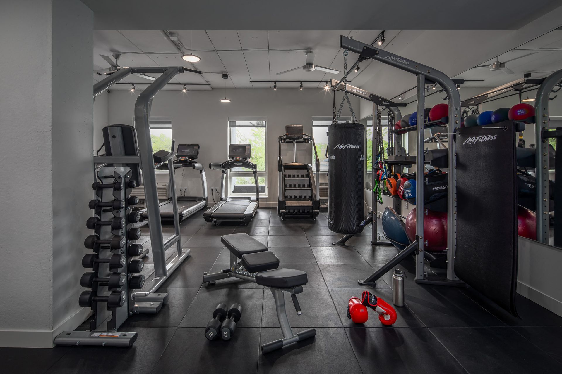 Interior view of a residential gym with treadmills, a weight rack, and a punching bag.