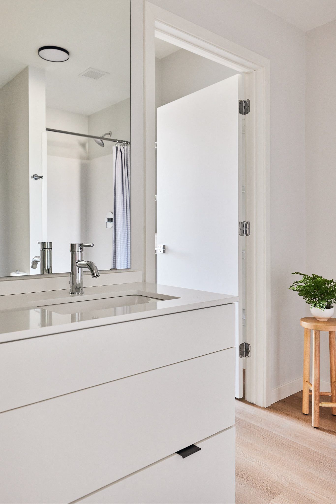 Modern white bathroom with a sleek vanity, chrome faucet, and large mirror.