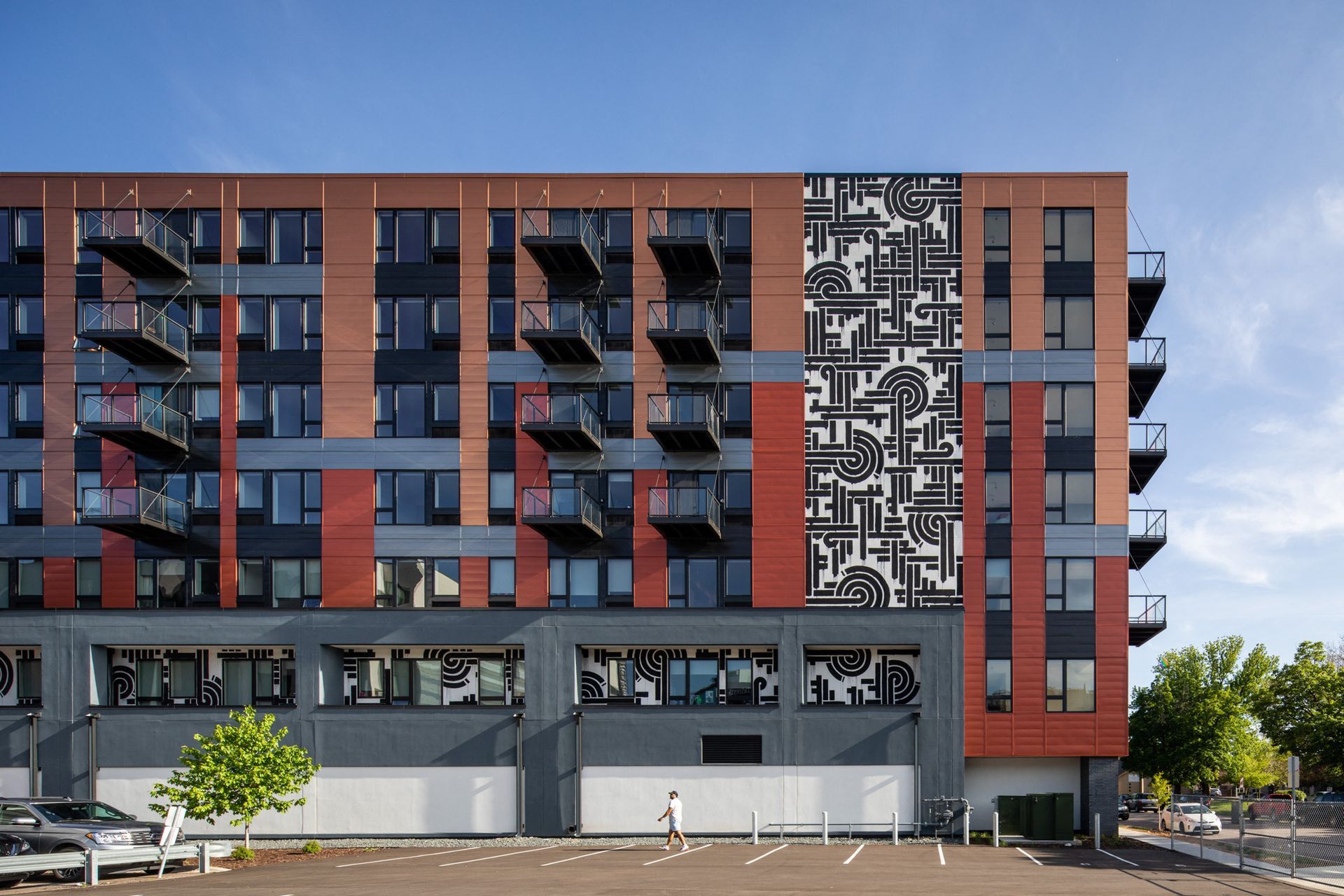 Exterior view of a modern apartment building with balconies and decorative mural panels.