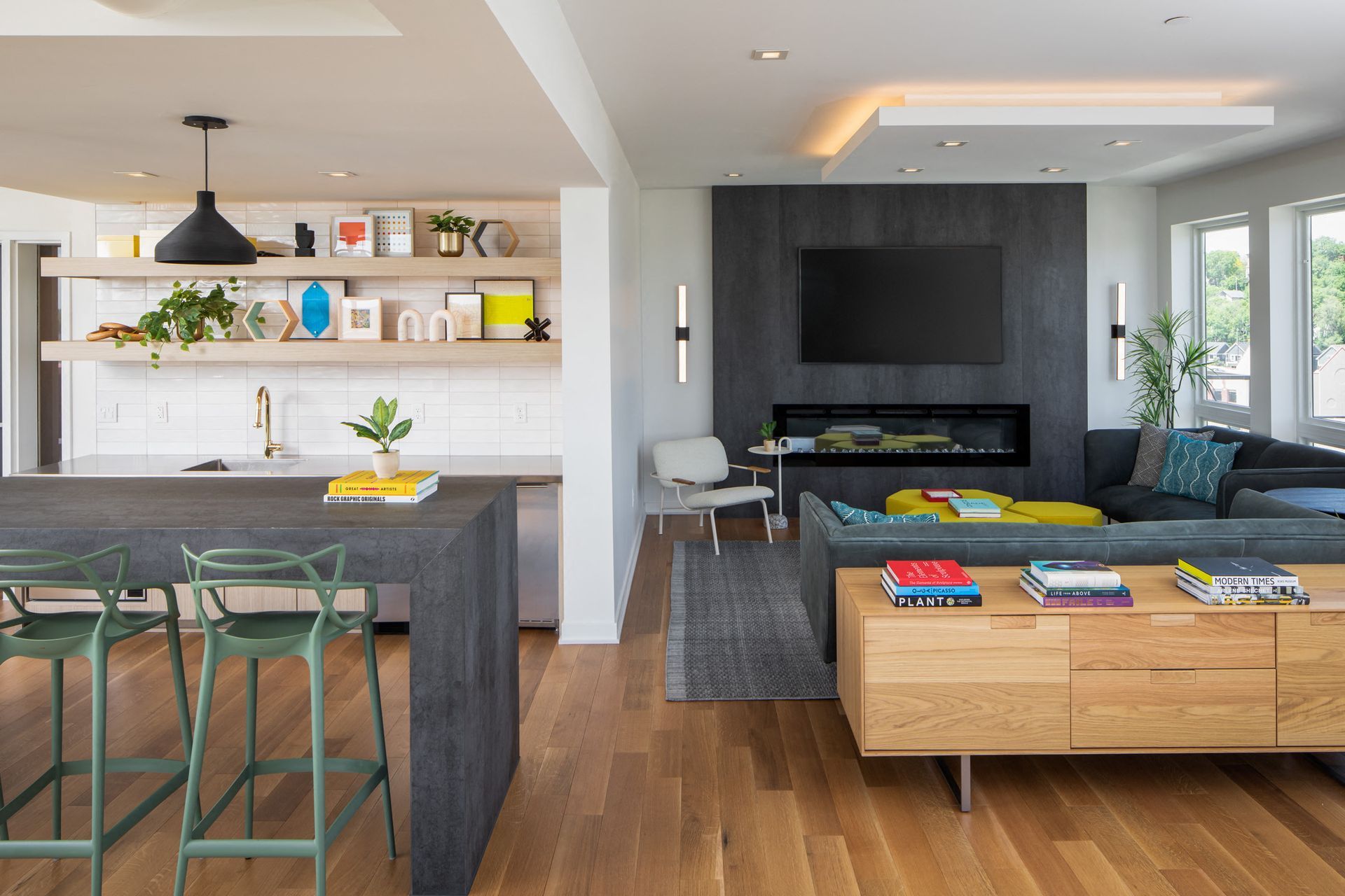 Open-concept kitchen and living area with a large island, floating shelves, and a fireplace wall.