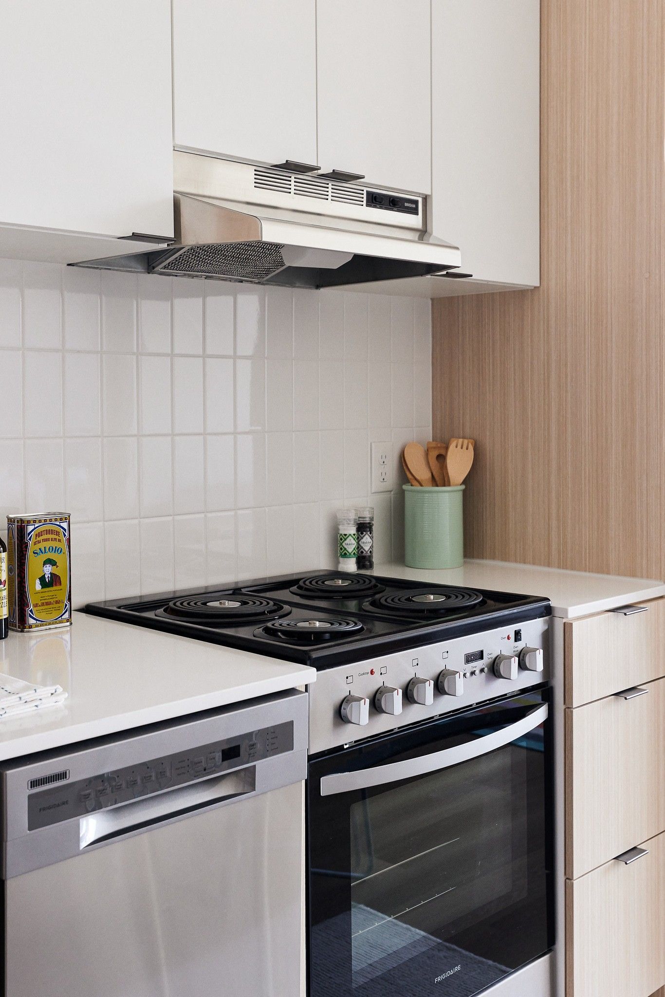 Kitchen in an apartment with white cabinets, tile backsplash, and stainless steel stove.