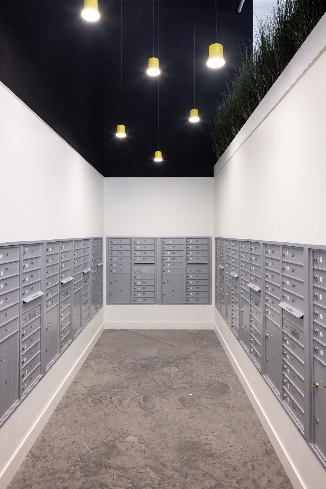 Hallway mailroom with rows of grey metal mailboxes along white walls