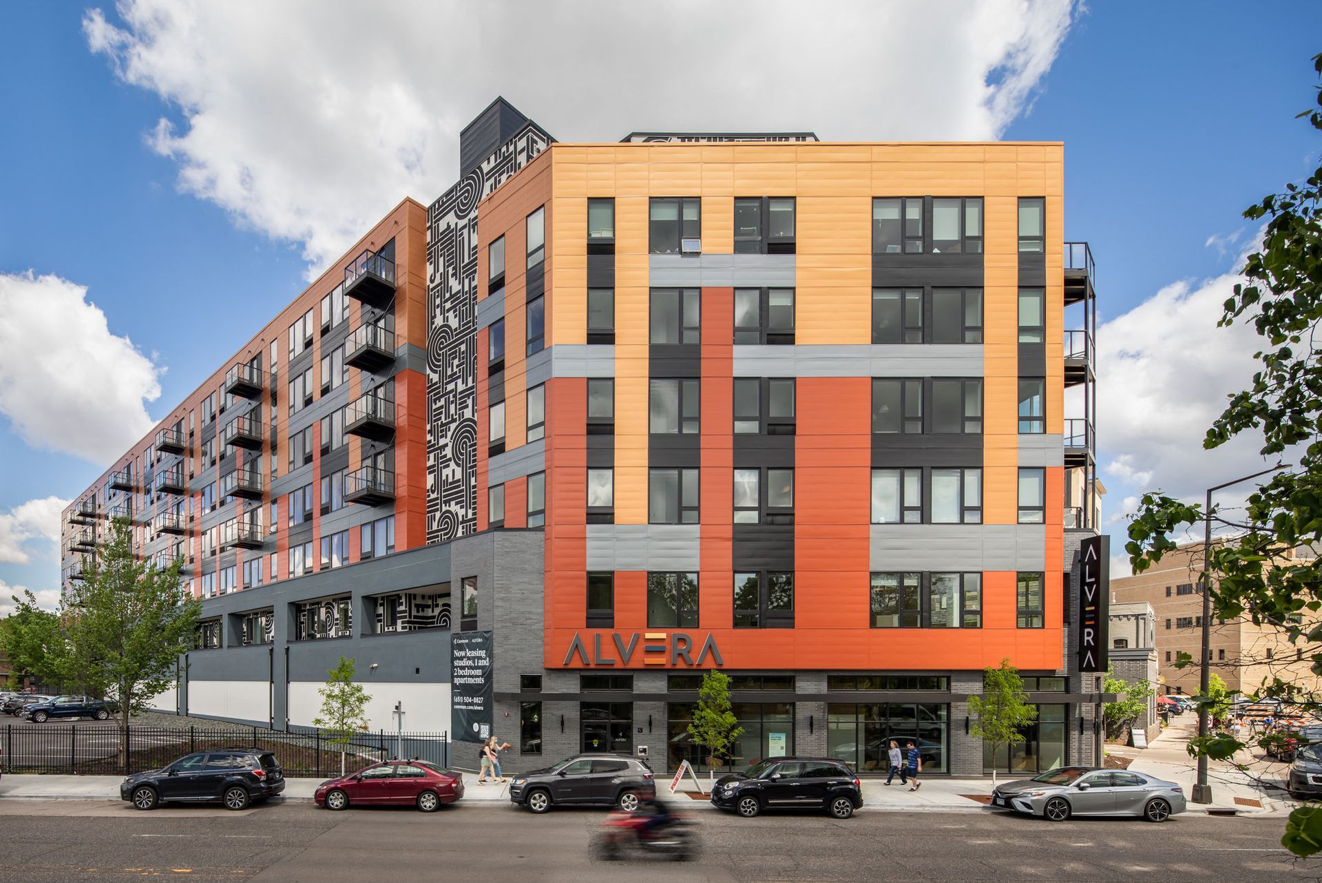 Exterior view of a colorful, multi-story apartment building with balconies along the street.