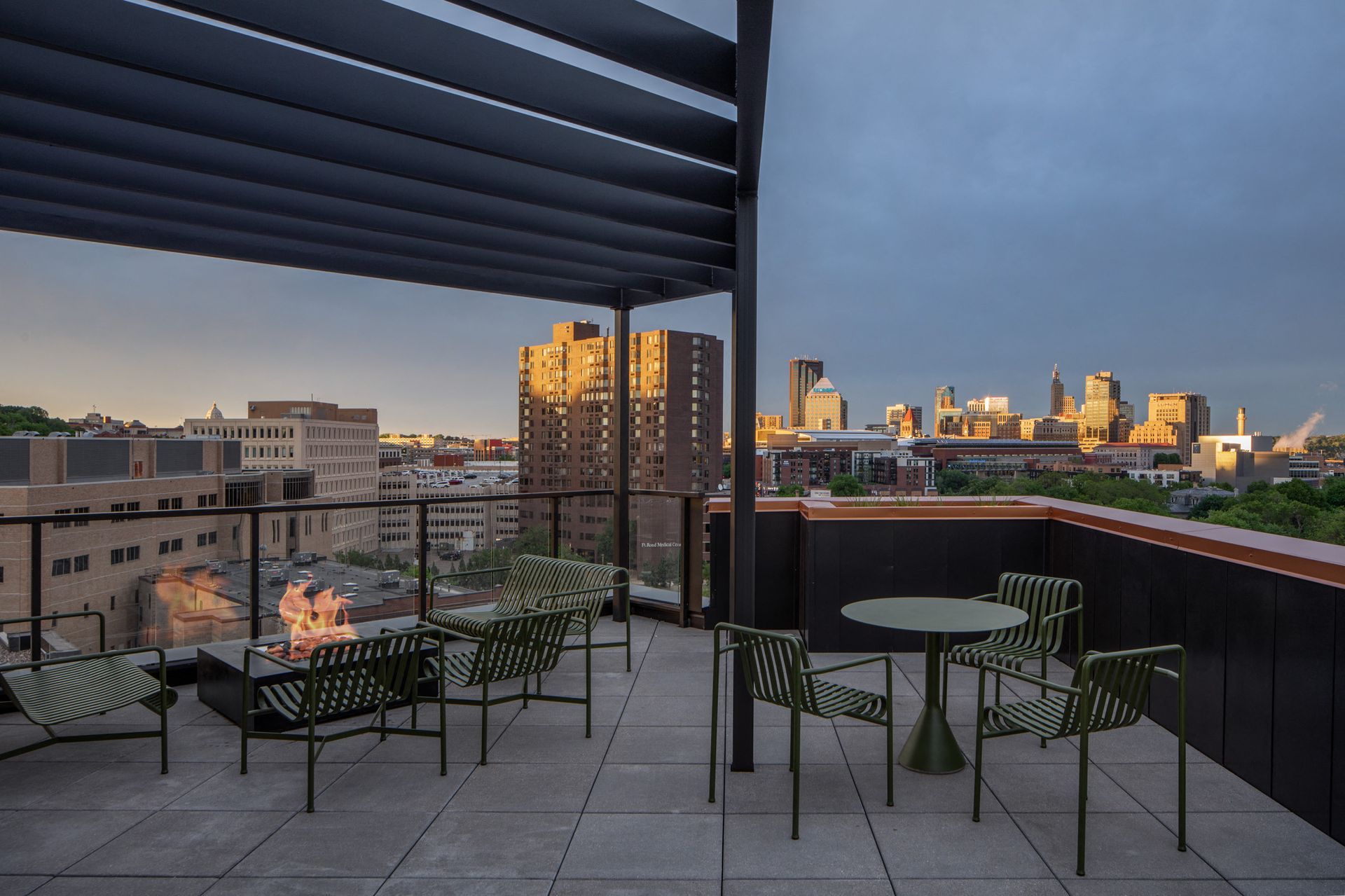 Outdoor rooftop lounge with a fire pit and skyline view.