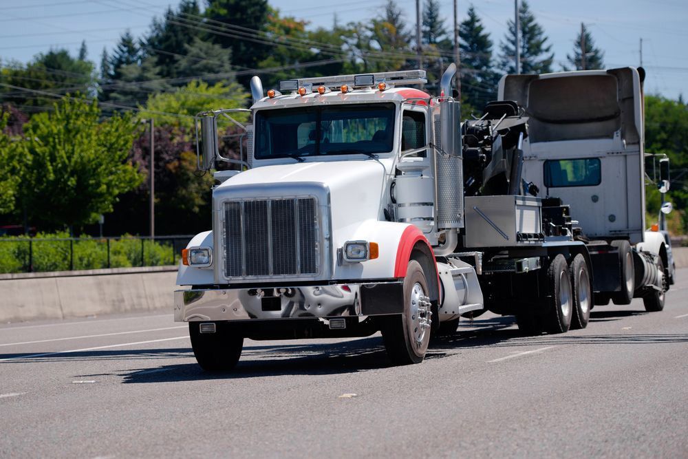 Big Towing Truck Tows The truck On A Highway With Green Trees — Grafton Heavy Towing In Grafton NSW