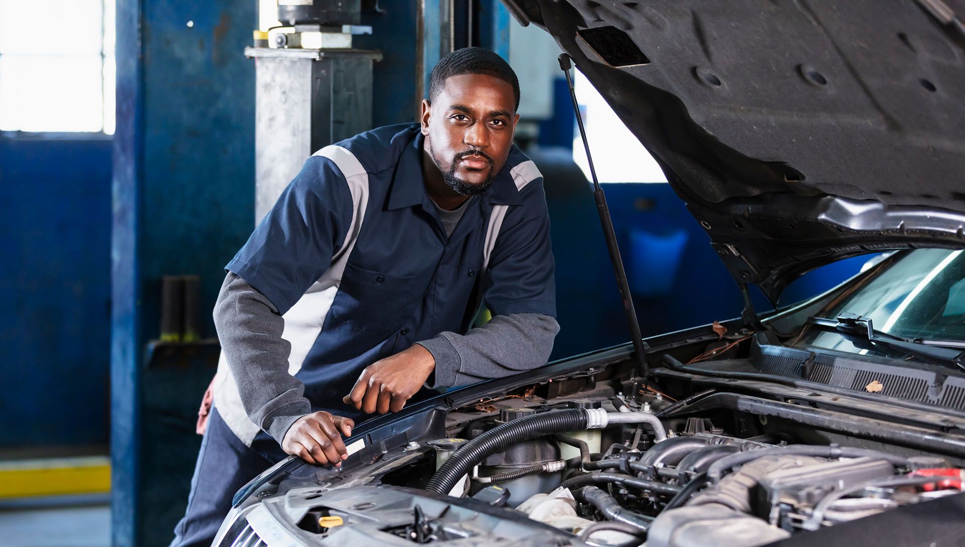 An auto mechanic inspecting a car engine. An auto mechanic inspecting a car engine.