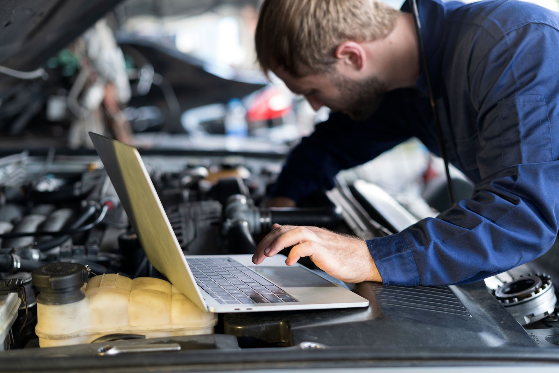 A mechanic is using a laptop to diagnose a car. A mechanic is using a laptop to diagnose a car.